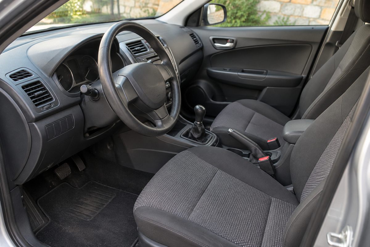 Sièges avant, volant et console d’une voiture d’occasion vus par la porte ouverte